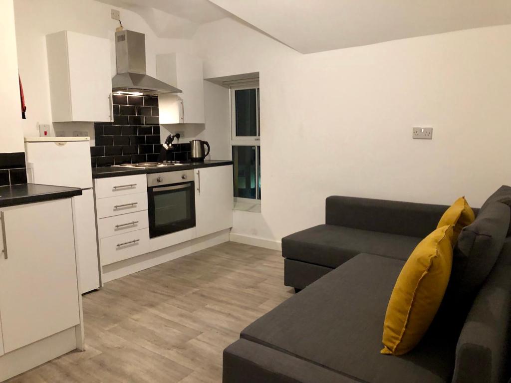 a living room with a couch and a kitchen at Smart central apartment, 5 mins from centre in Cardiff