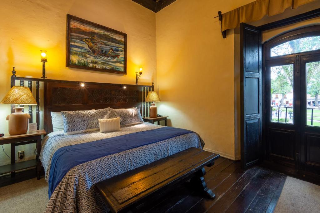 Schlafzimmer mit einem Bett und einer Holzbank in der Unterkunft Hotel Mansion Iturbe in Pátzcuaro