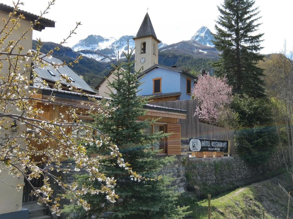 un bâtiment avec une église et une tour d'horloge dans l'établissement Auberge du Bachelard, à Uvernet