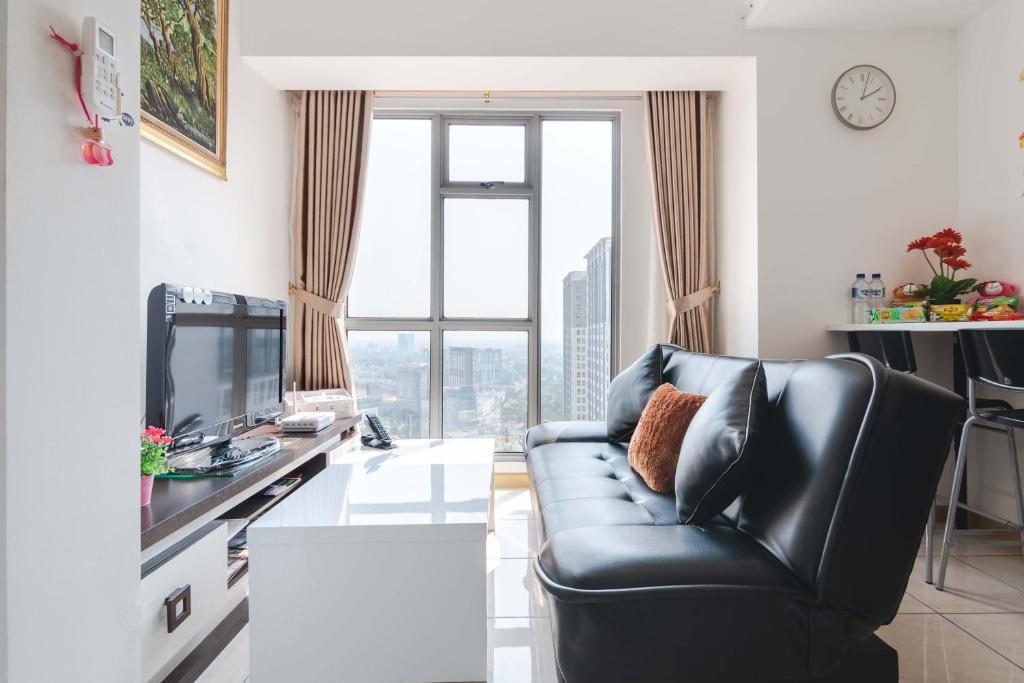 a living room with a black leather couch and a tv at M-Town Residence 1 BR Comfy Tangerang in Tangerang