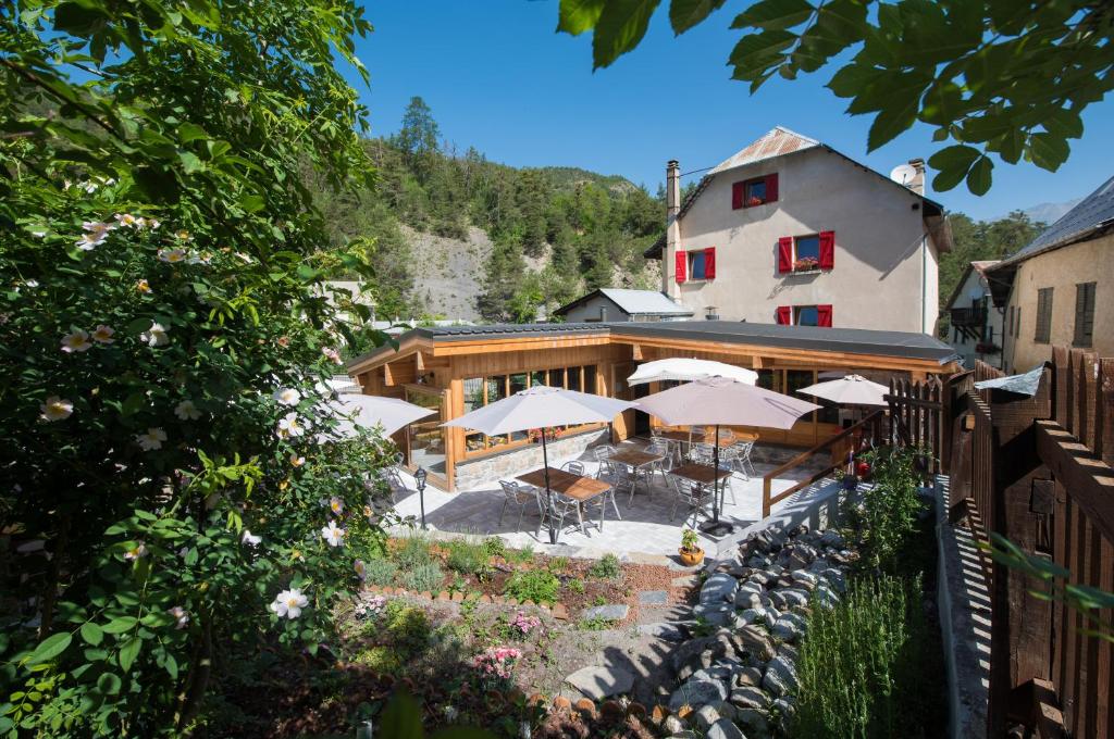 a building with tables and umbrellas in front of it at Auberge du Bachelard in Uvernet