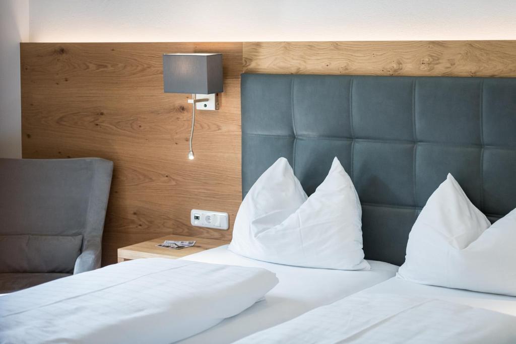 a bedroom with a bed with white pillows and a headboard at Hotel Plankenhof B&B in Pill