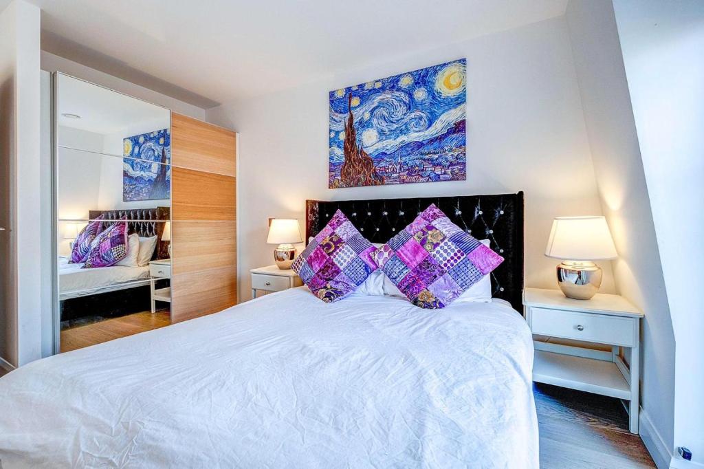 1 dormitorio con 1 cama blanca grande con almohadas moradas en Charles Dickens, Tate Modern Apartments en Londres