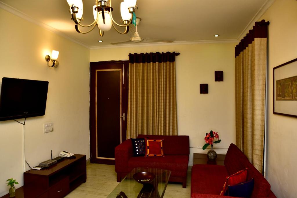 sala de estar con sofá rojo y TV en 2BHK Comfortable Furnished Serviced Apartments in Hauz Khas - Woodpecker Apartments, en Nueva Delhi