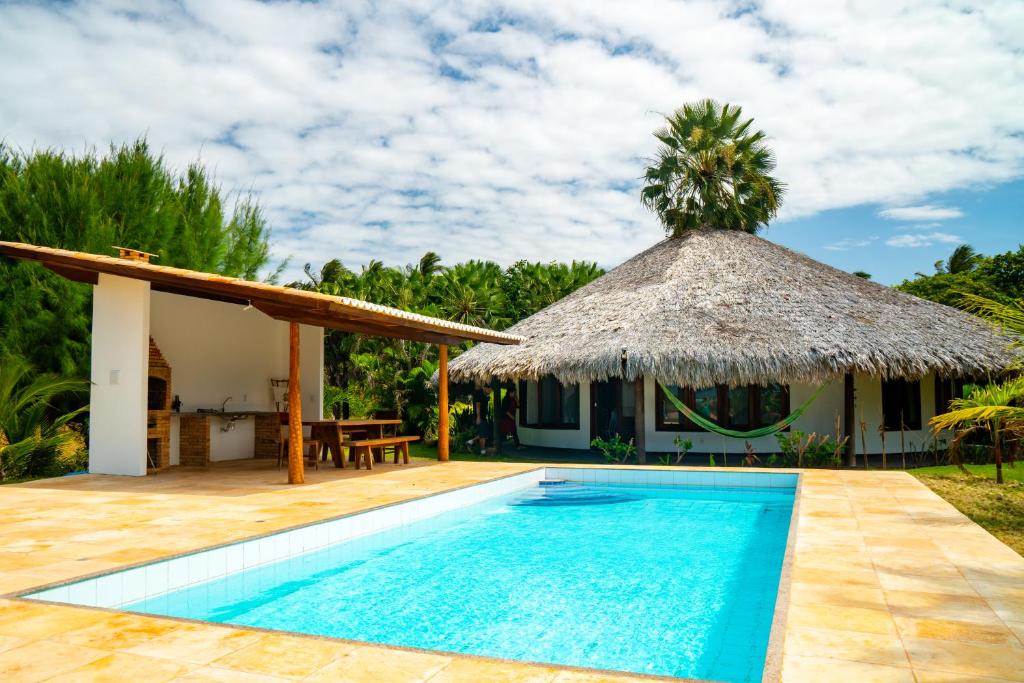 une villa avec une piscine et un toit de chaume dans l'établissement Refugios Parajuru - Villa Alegre, à Parajuru