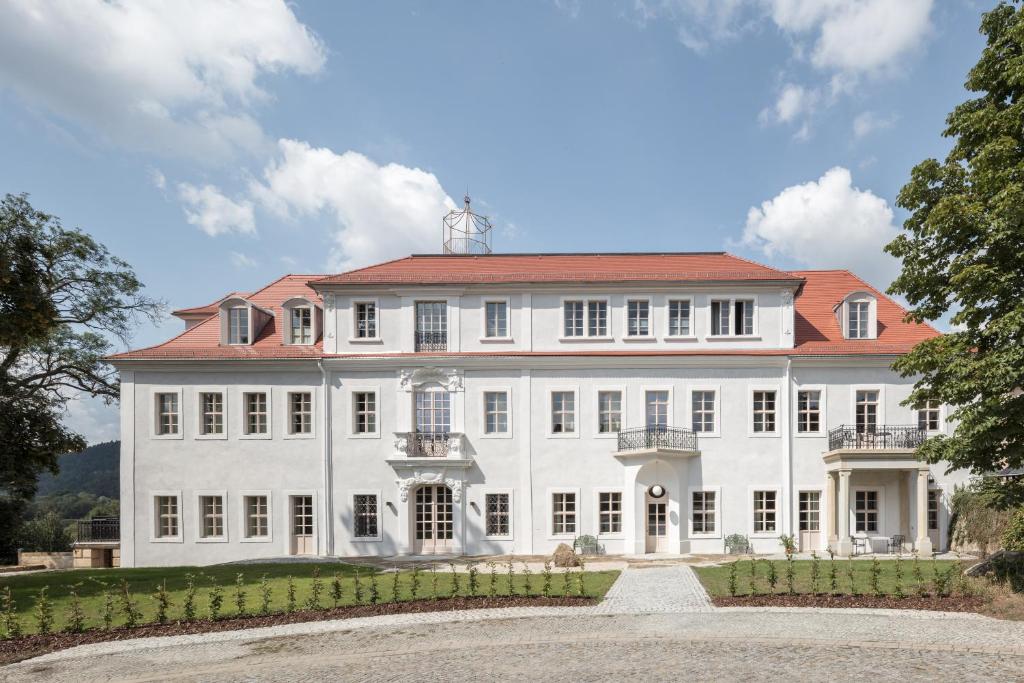 uma grande mansão branca com um telhado vermelho em Schloss Prossen em Bad Schandau