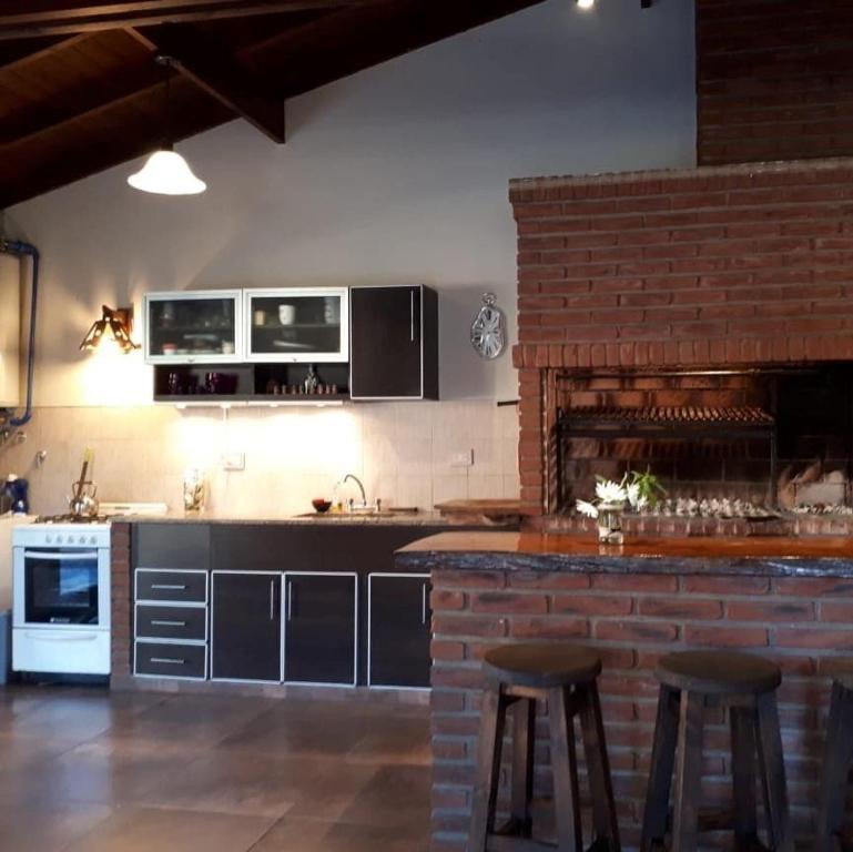 une cuisine avec un comptoir avec des tabourets et une cheminée dans l'établissement Bosque Peralta Ramos. Zorzales del Bosque, à Mar del Plata