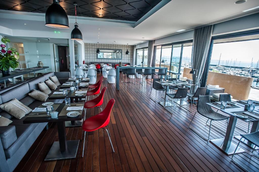 a restaurant with tables and red chairs in a room at Pestana Cidadela Cascais - Pousada & Art District in Cascais