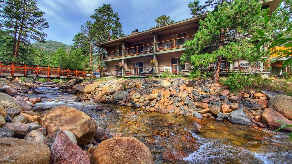 a large stone building with a river running through it at The Inn on Fall River & Fall River Cabins in Estes Park