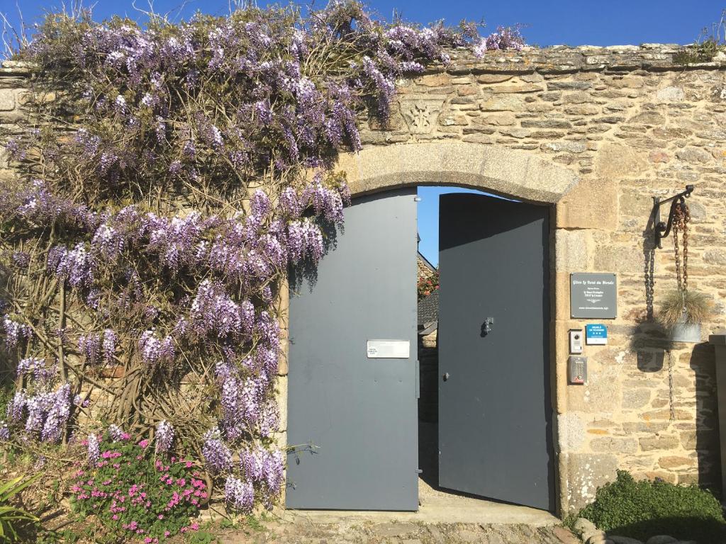ル・コンケにあるGîtes Le Bout du Mondeの紫花の花輪のある石造りの建物の入口