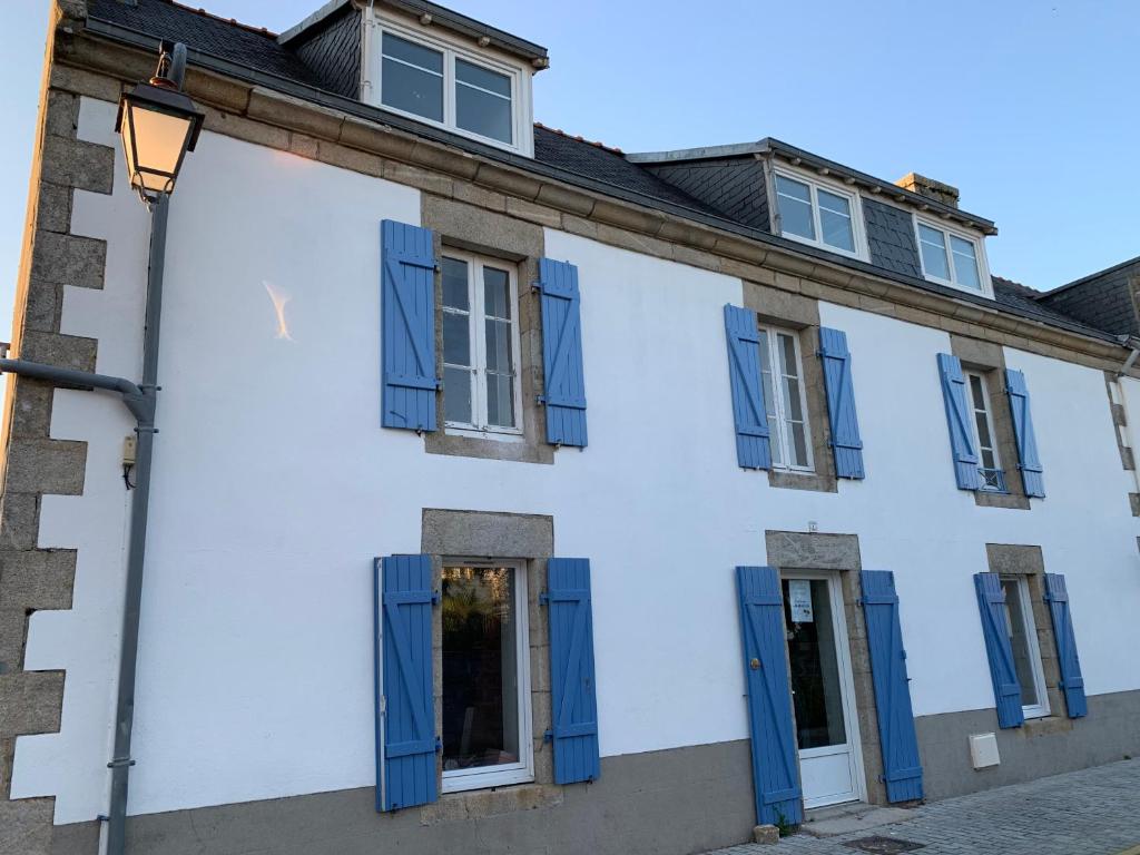 a white building with blue shutters and a street light at Jolie maison au port de l’Ile Tudy in Île-Tudy