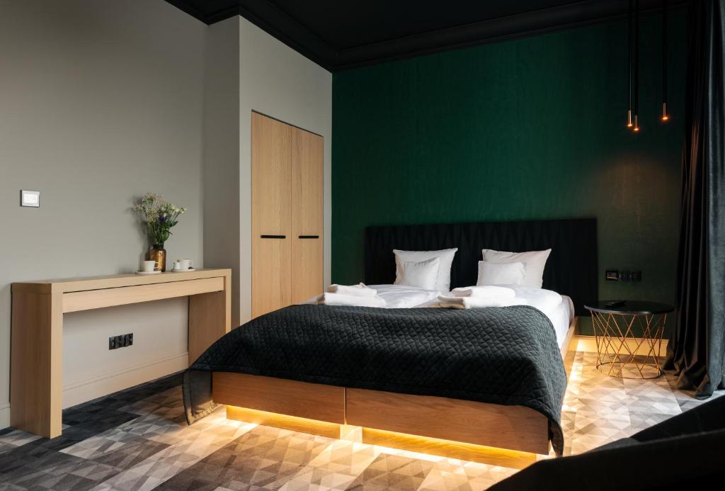 een slaapkamer met een groot bed met een groene muur bij Sansara Apartments in Bydgoszcz