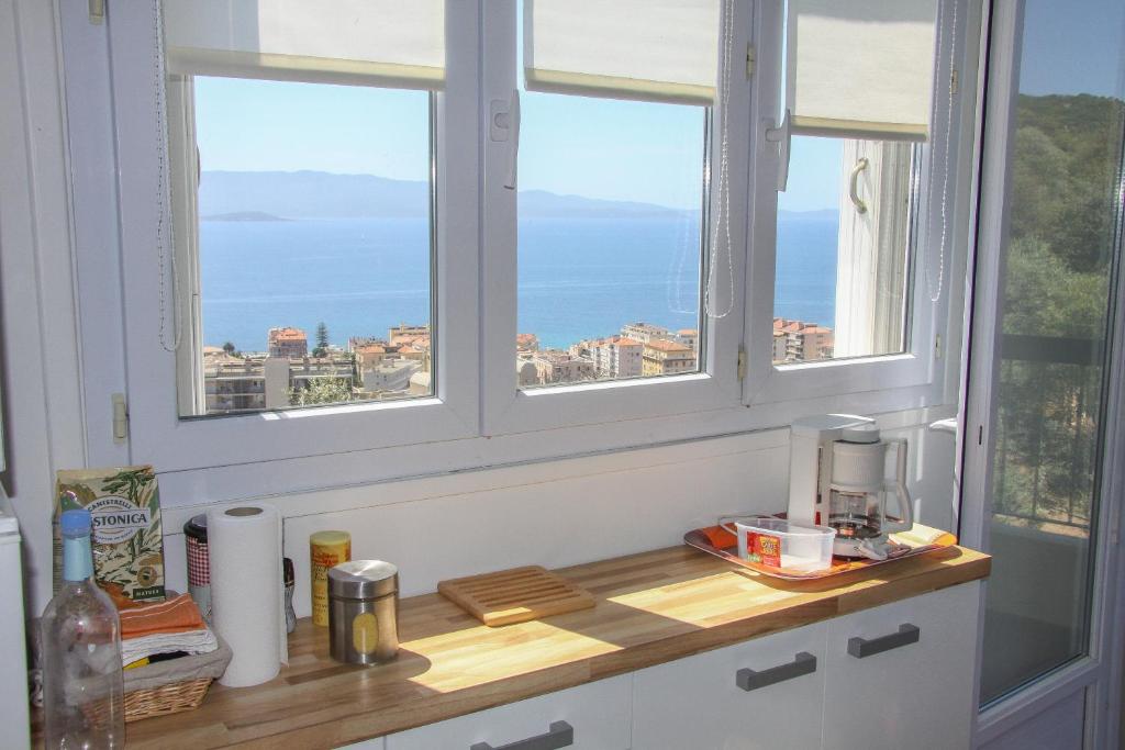 cocina con 2 ventanas y encimera con sofá en Appartement vue mer, en Ajaccio