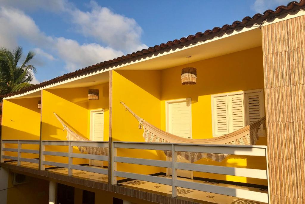 a yellow house with a balcony at Flor Amarela in São Miguel dos Milagres