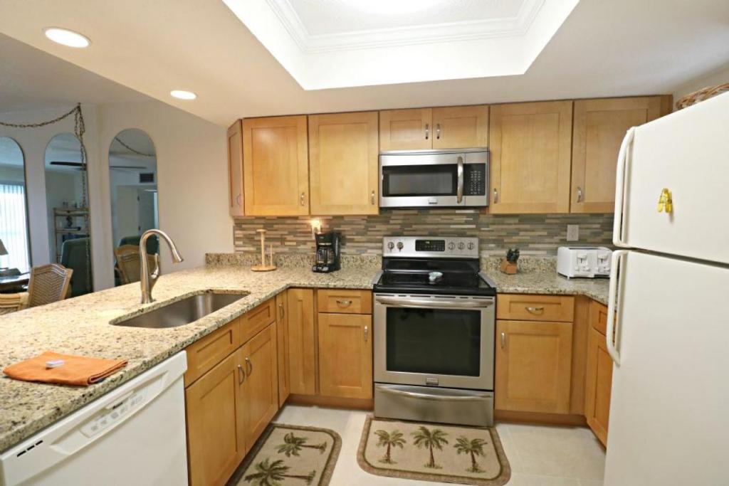 eine Küche mit Holzschränken und einem weißen Kühlschrank in der Unterkunft Ocean Village Club O36 in St. Augustine