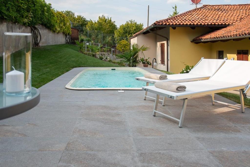 ein Pool mit einer Bank neben einem Haus in der Unterkunft B&B Villa Fulvia in Alba