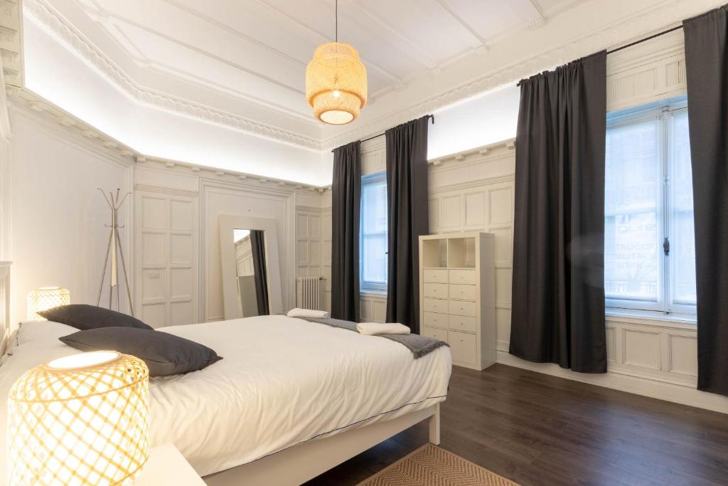 a white bedroom with a large white bed and windows at CENTRAL by Kyosai in Bilbao