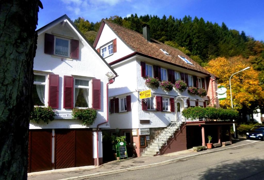una casa blanca con persianas rojas en una calle en Pension Zur Rose, en Bad Peterstal-Griesbach