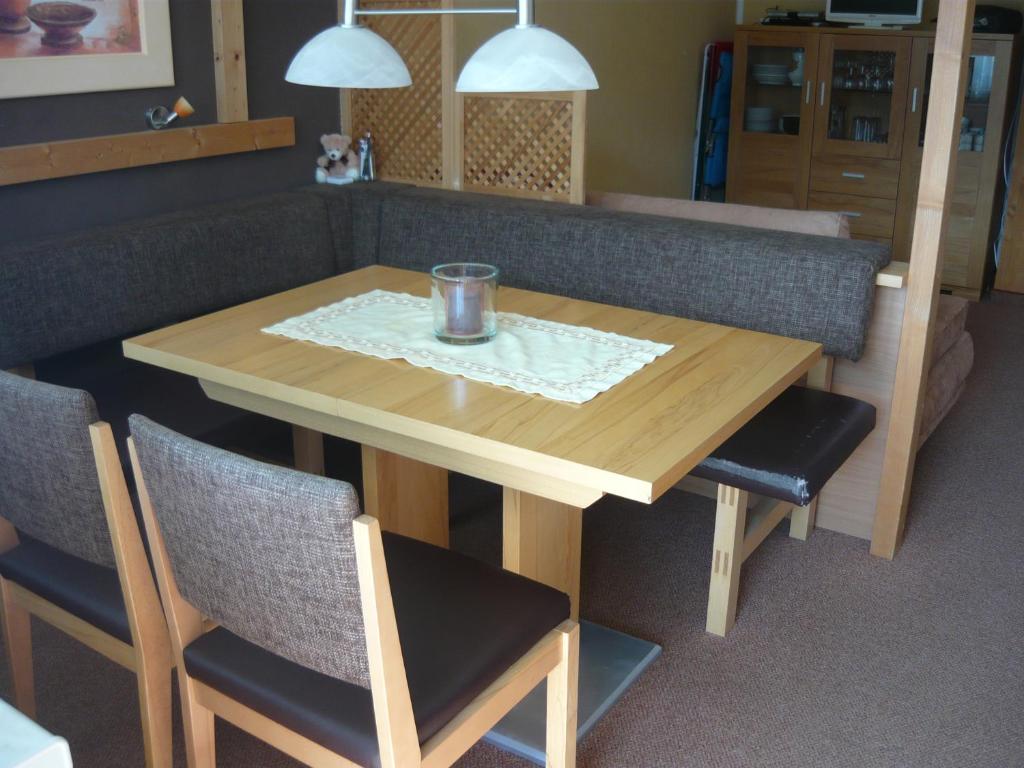 a wooden table with two chairs and a glass on it at Ferienwohnung Riedberg in Balderschwang