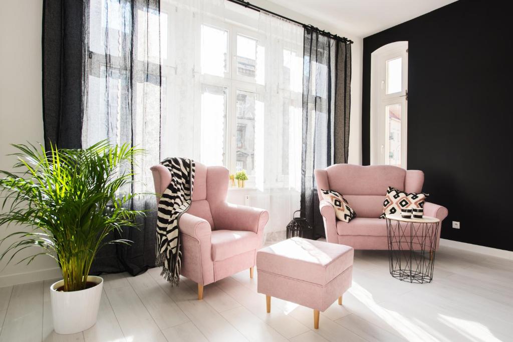 sala de estar con 2 sillas rosas y mesa en Legnica Apartament 82m2 Delux 5, en Legnica
