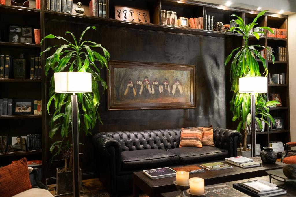 una sala de estar con un sofá de cuero negro y una pintura en Legado Mitico Salta Hotel Boutique en Salta