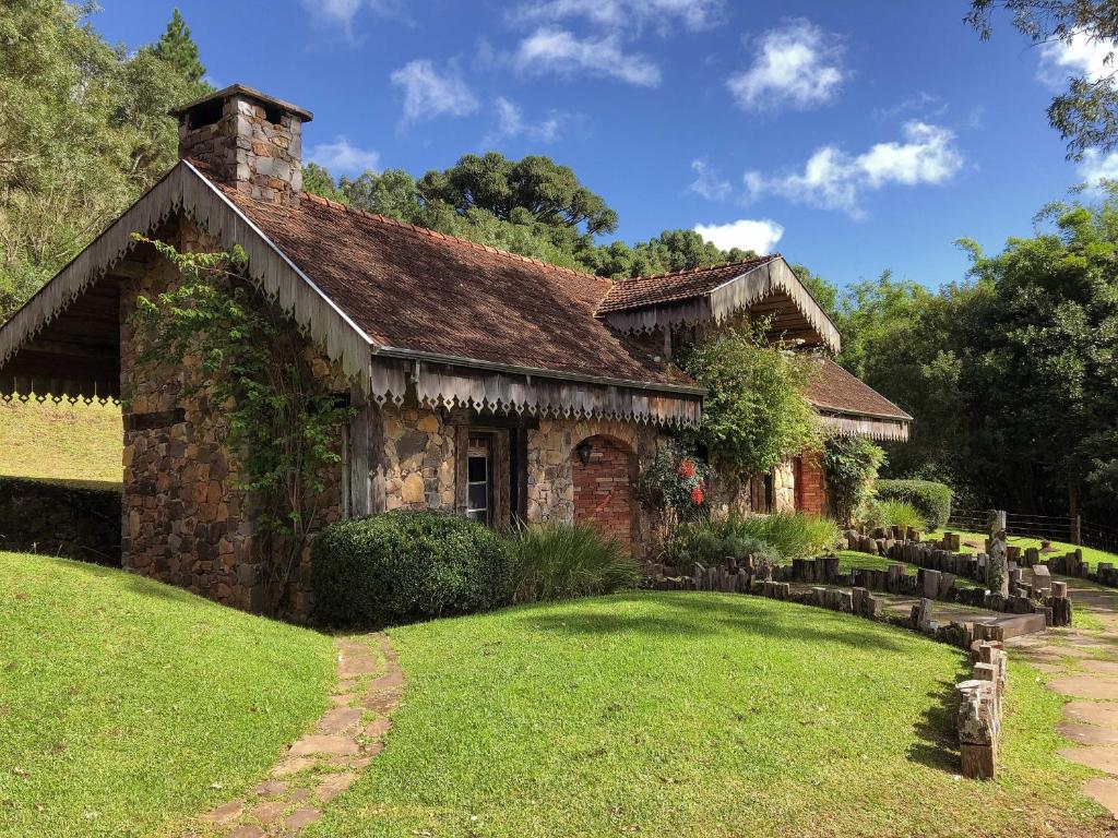 una antigua casa de piedra con un patio de césped en Estalagem La Hacienda, en Gramado