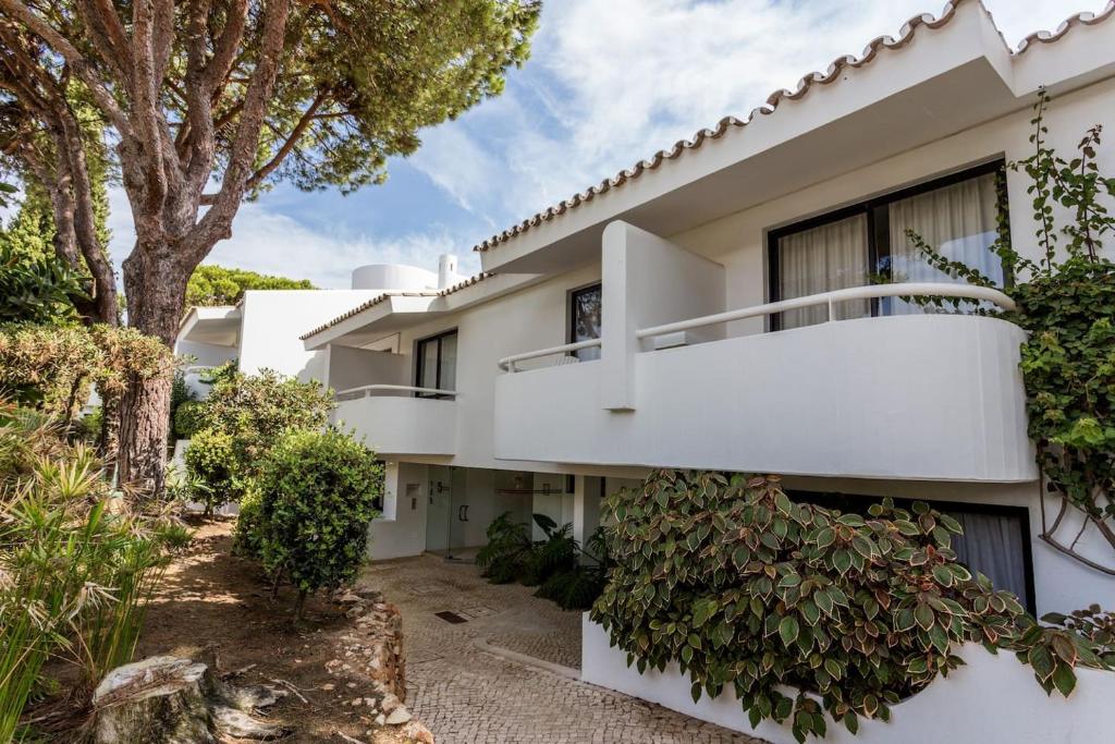 an exterior view of a white house with a tree at 1Bed Apart Quinta do Lago in Almancil