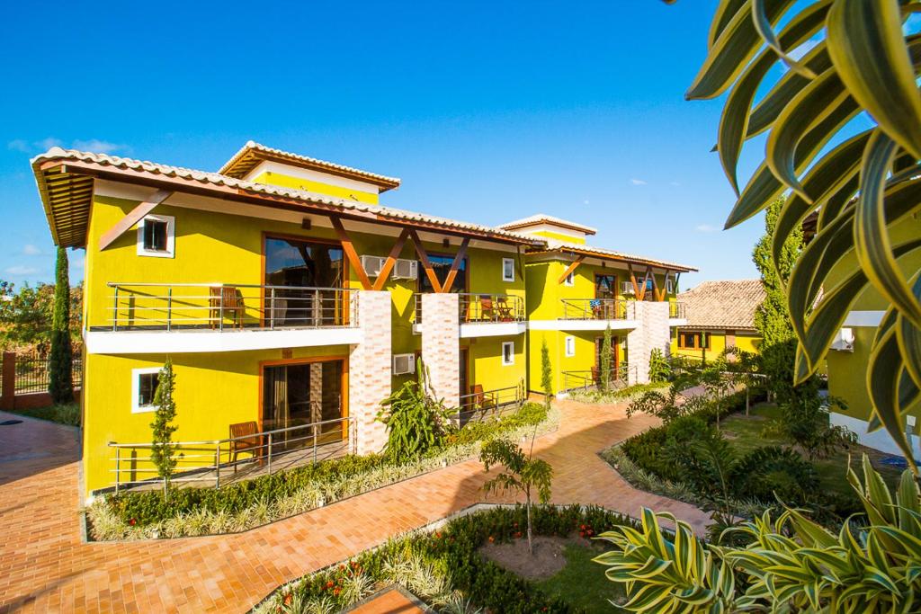 a yellow house with a lot of landscaping at Vila Miola Hotel in Porto Seguro