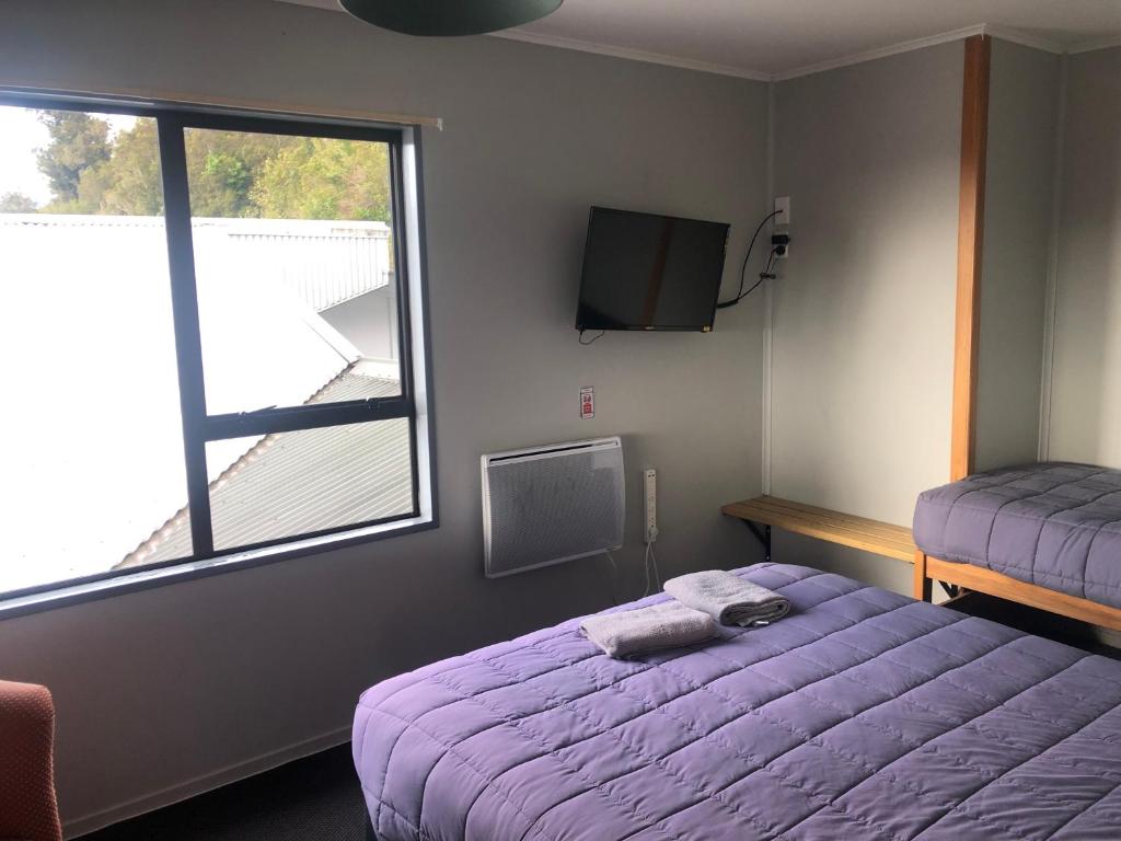 um quarto com uma cama roxa e uma janela em Ivorytowers Accommodation em Fox Glacier