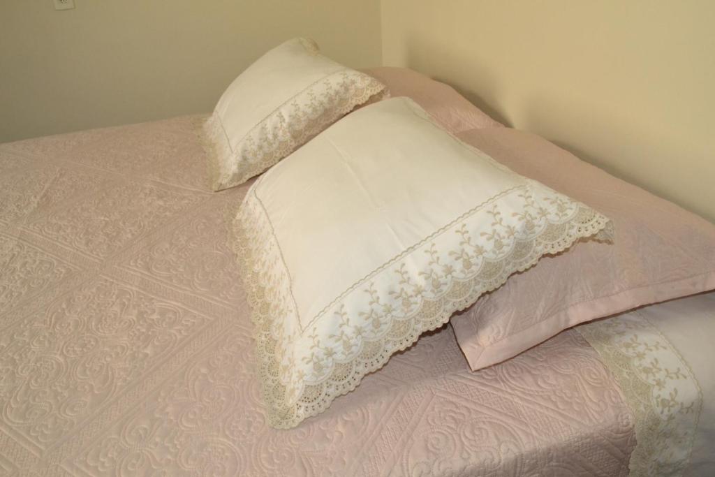 Casa Premiatto في أولامبرا: سرير عليه وسائد وردية وبيضاء