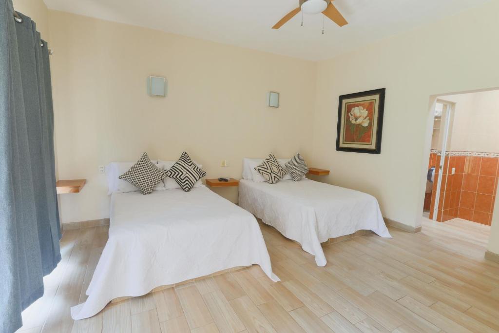 2 Betten in einem Zimmer mit weißen Wänden und Holzböden in der Unterkunft Habitaciones Lucero 4 in Santa María del Oro