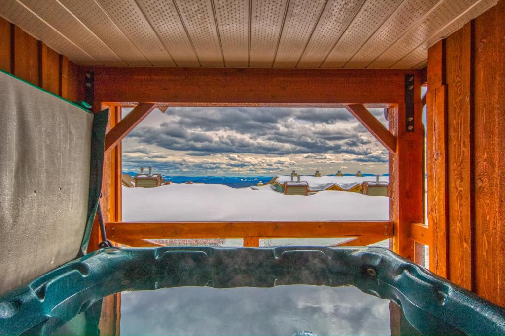 Blick aus dem Fenster einer Badewanne mit Blick auf den Schnee in der Unterkunft 3 BR 3 Bath ski in ski out with private hot tub in Big White