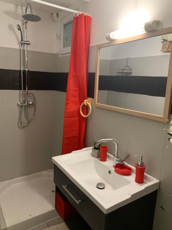 a bathroom with a sink and a red shower curtain at Pois doux in Fort-de-France