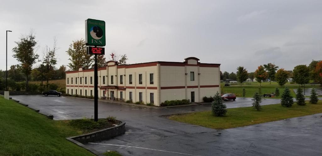 Pleasant Night Inn- carthage NY في West Carthage: مبنى في موقف للسيارات مع علامة في الأمام