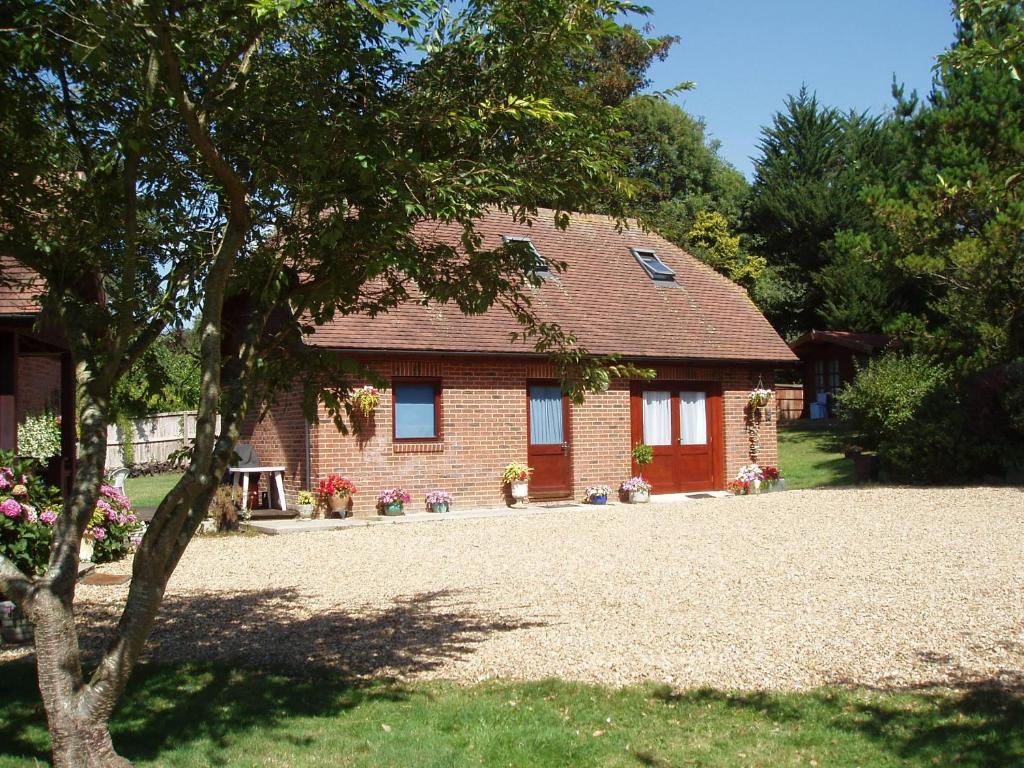 a brick house with a gravel driveway in front of it at Clock House Cottage in Brook