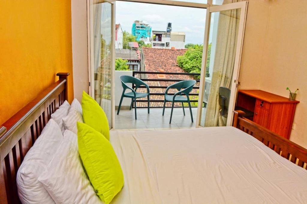 1 dormitorio con 1 cama y balcón con sillas en Furnished apartment at Colombo suburbs Nawala, en Rajagiriya