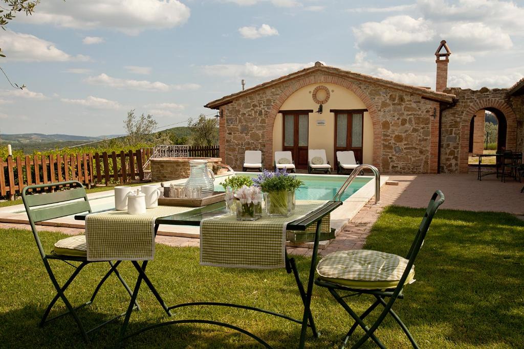 un patio con mesa, sillas y piscina en Agriturismo Ripaiani, en Marsciano