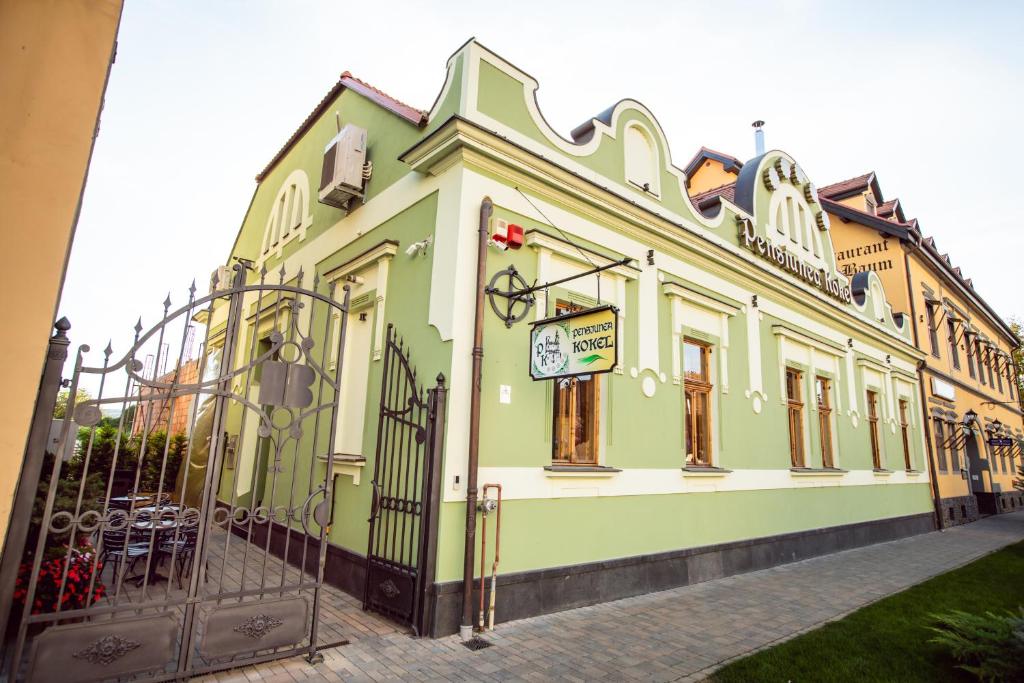 Dumbrăveni的住宿－Pension Kokel，绿色和白色的建筑,设有大门