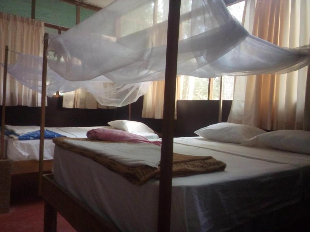 a bedroom with two beds with a canopy bed at Tambopata River in Puerto Maldonado