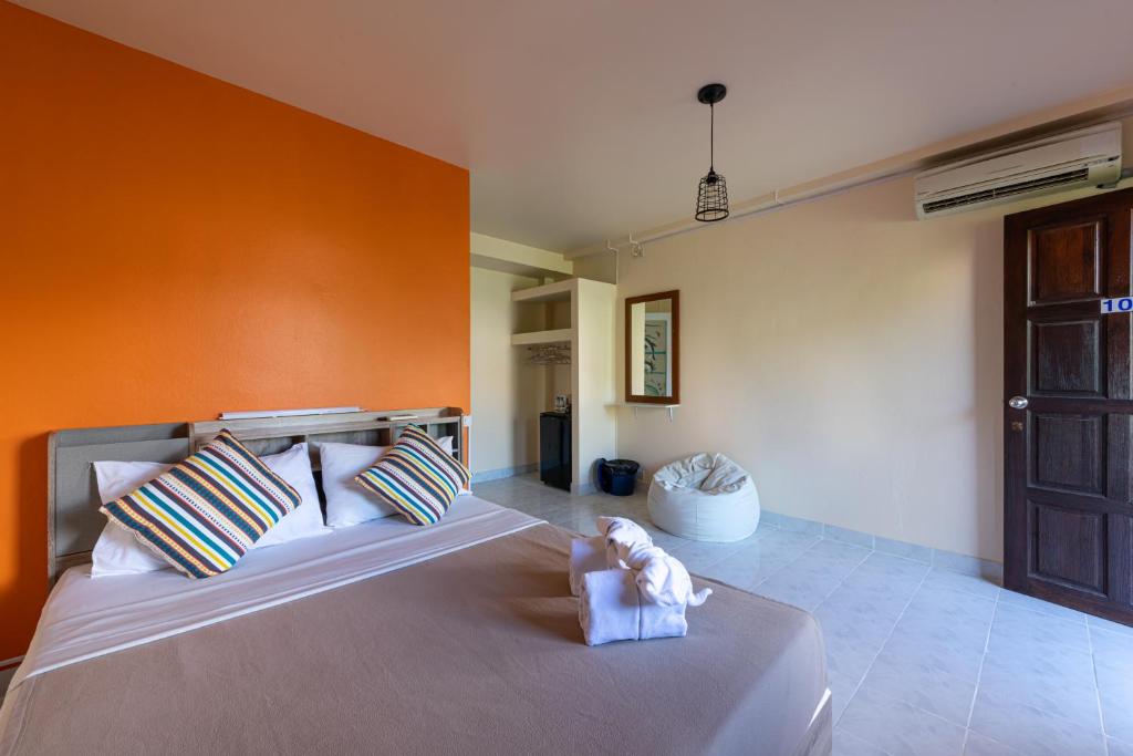 a bedroom with a large bed with an orange wall at myPatong Social Hostel in Patong Beach