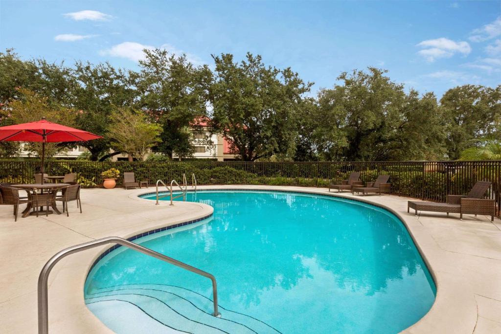 a swimming pool with a table and chairs and an umbrella at Ramada by Wyndham Suites Orlando Airport in Orlando