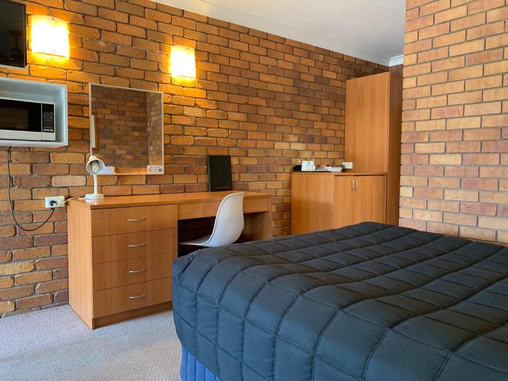a bedroom with a bed and a brick wall at Peter Allen Motor Inn in Tenterfield