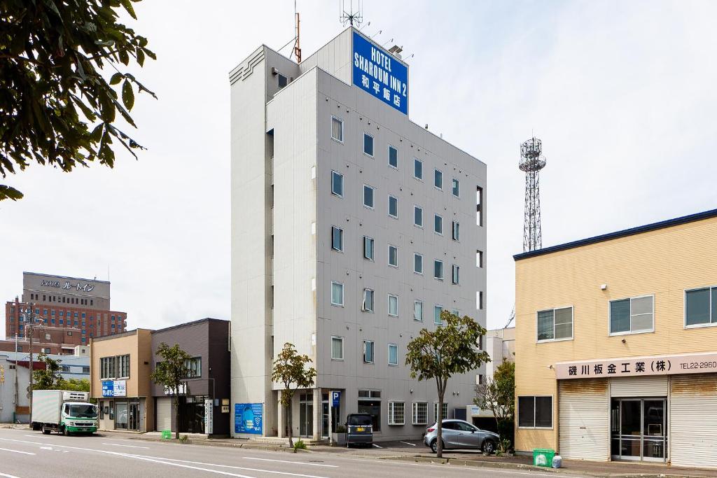 een wit gebouw met een bord erop bij Hotel Sharoum Inn 2 in Hakodate