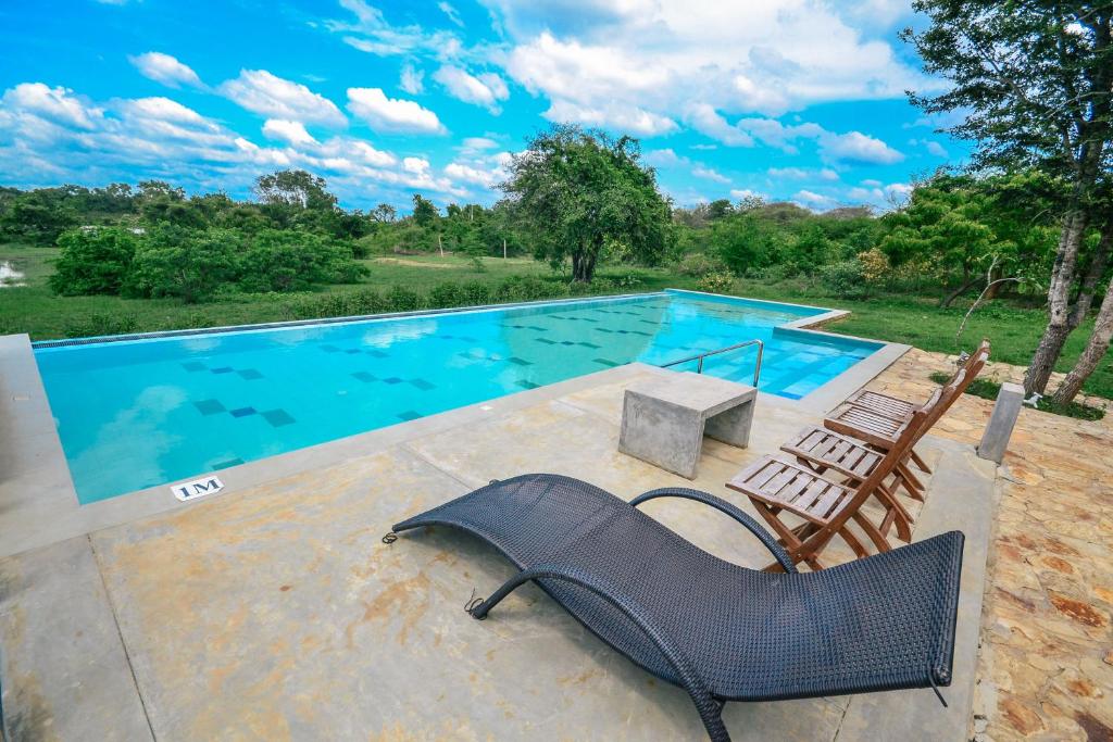 a swimming pool with a chair and a couch next to it at Back of beyond - Wellness Retreat in Tangalle