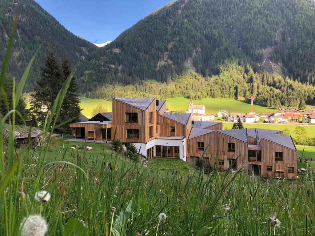 una casa in un campo con montagne sullo sfondo di Bio Natur Refugium Blaslahof **** a Valle Di Casies