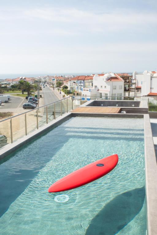a red surfboard in the water in a swimming pool at Surfers Lodge Peniche in Peniche