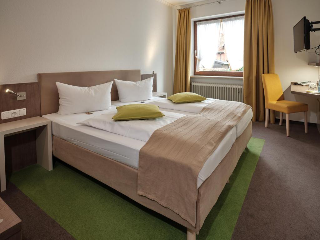 a bedroom with a large bed and a desk at Hotel Gasthaus zur Linde in Seevetal