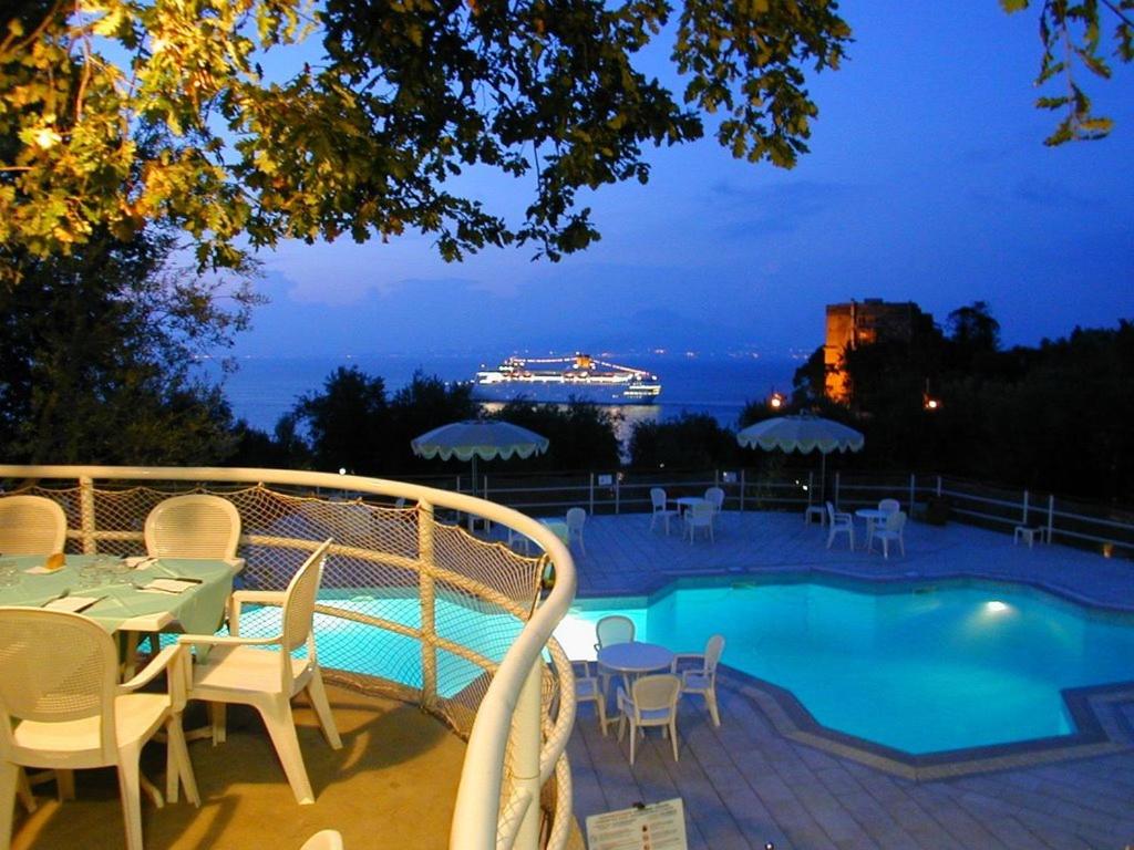 a pool with a table and chairs and a cruise ship at Camping Nube D'Argento in Sorrento