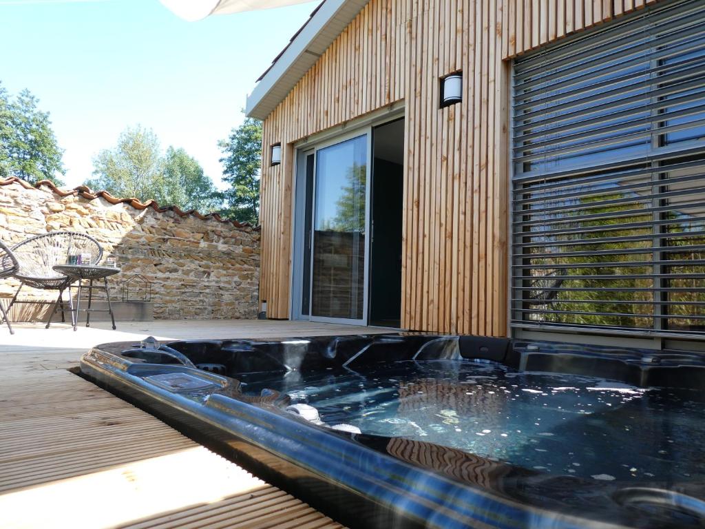 einen Whirlpool auf einer Terrasse neben einem Gebäude in der Unterkunft L ABRI spa et détente in Liergues