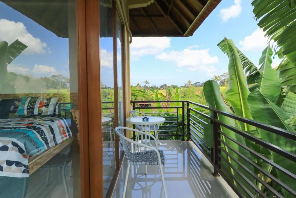 a room with a balcony with a bed and a table at Sunari Guest House in Canggu